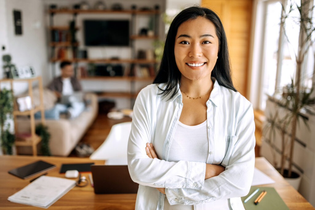 Young asian business woman posing in front of her desk i home office setup