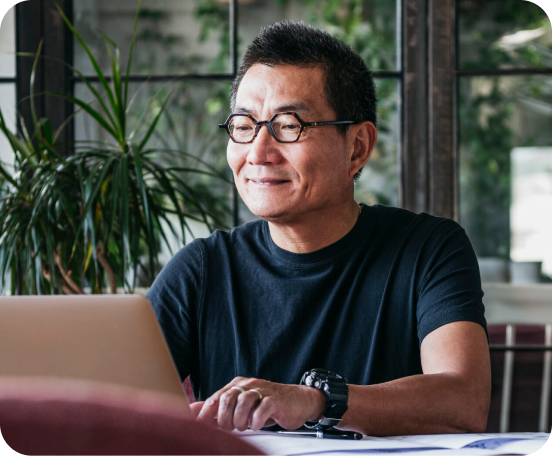 Mature man in glasses at home, typing on computer, contented, small business owner